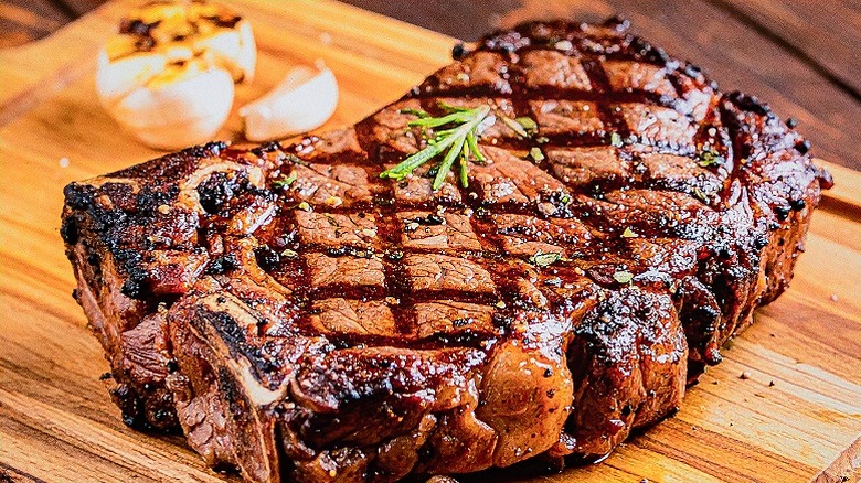 Juicy Grilled Ribeye Steak, Seared with Herbs and Garlic, Resting on a Wooden Board