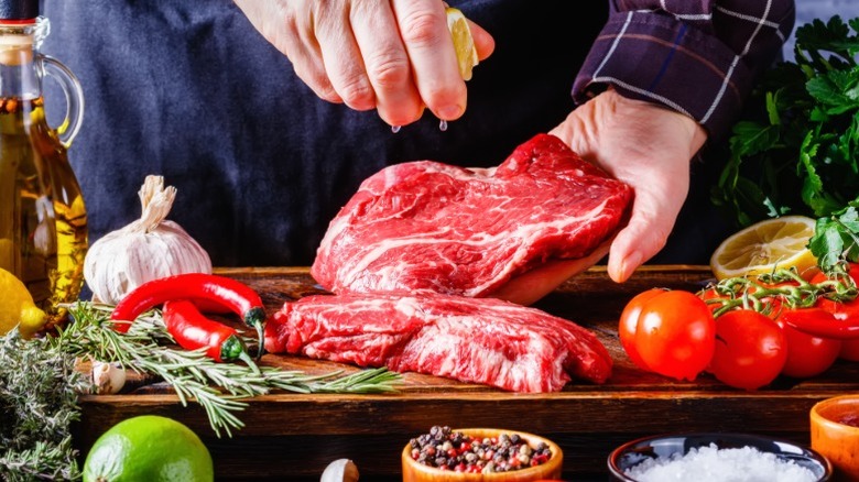 male chef drizzling lemon juice over the top of chuck eye beef steak, close-up