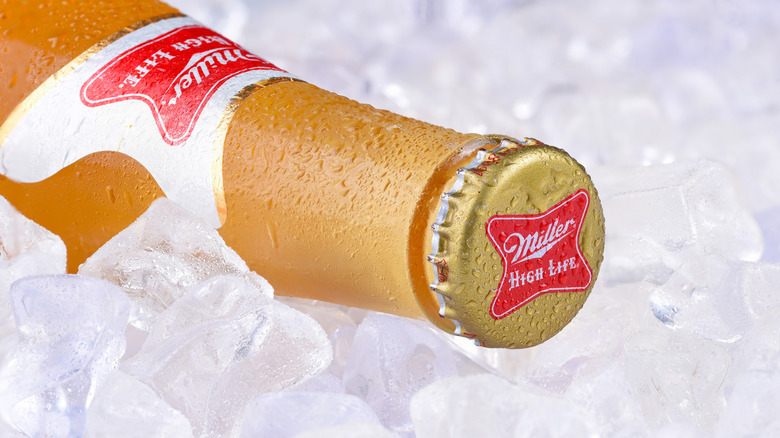 Miller High Life beer bottle on its side in ice, with its cap facing the camera