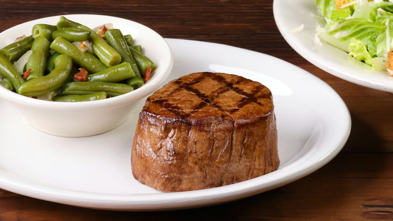A Dallas Filet from Texas Roadhouse and a bowl of green beans on a white plate