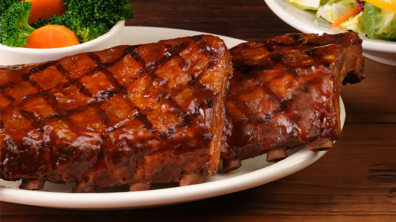 A full slab of Texas Roadhouse ribs on a white plate against a wooden surface