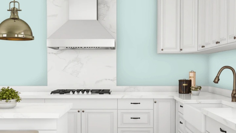 Kitchen with white marble countertops, white cabinets, blue walls