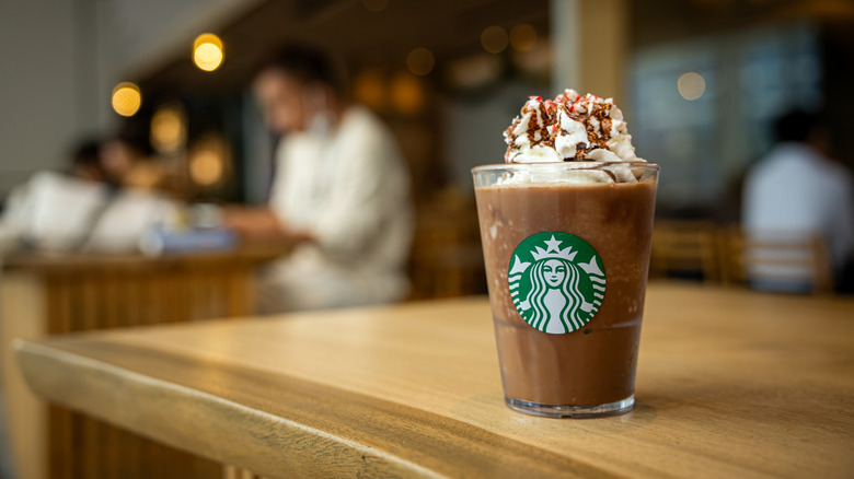 Mocha drink with whipped cream in a glass Starbucks cup