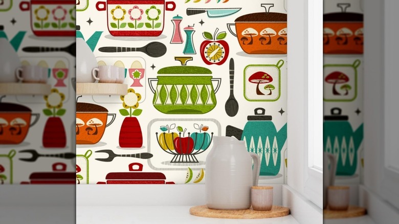 Items on a white kitchen countertop in front of 1950s-style wallpaper with a colorful kitchen appliance theme