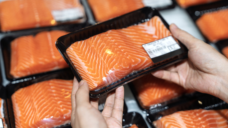Hands holding salmon fillet in packaging
