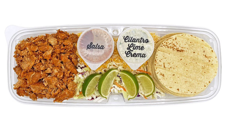 Chicken taco kit in a plastic tray, with lime wedges and dips