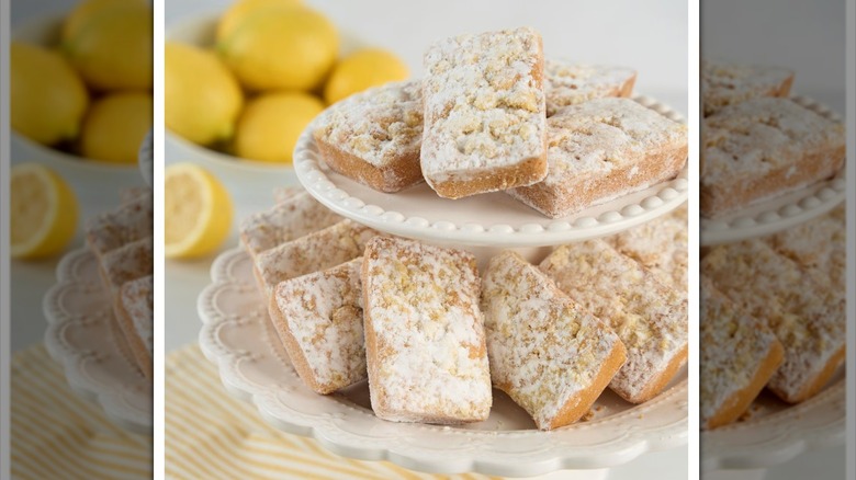 Two-tiered platter of lemon blondie bars with bowl of lemons in background