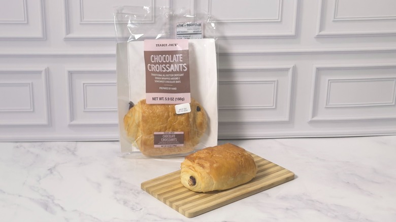 Package of Trader Joe's chocolate croissants and single croissant on a wooden cutting board