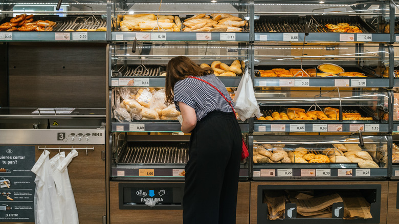 A woman selects baked goods at a grocery store