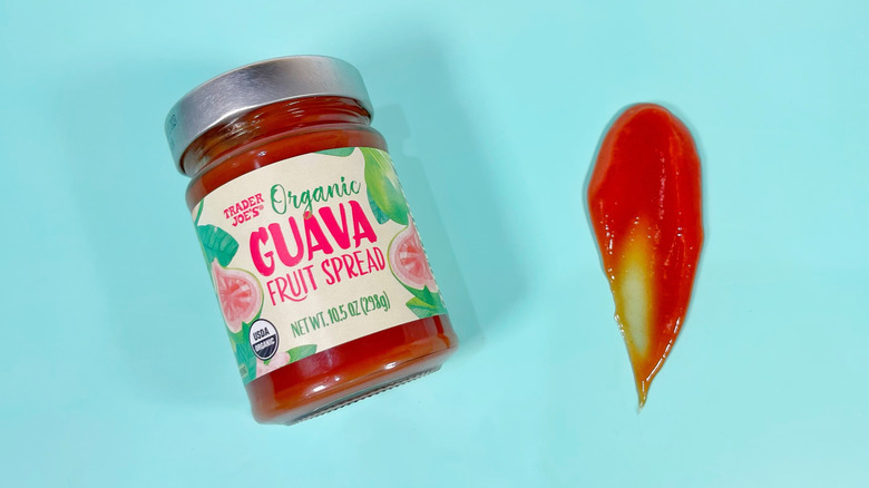 A jar of Trader Joe's guava fruit spread next to a spoonful on a blue background