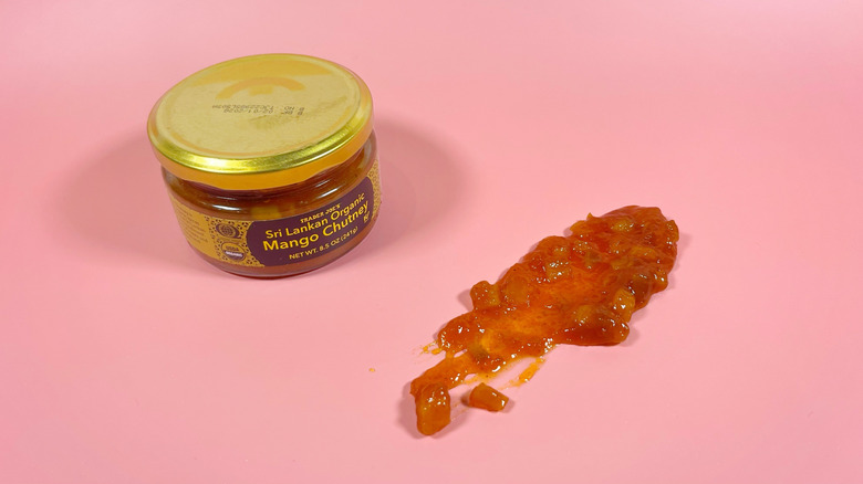 A jar of Trader Joe's mango chutney next to a schmear on a pink background