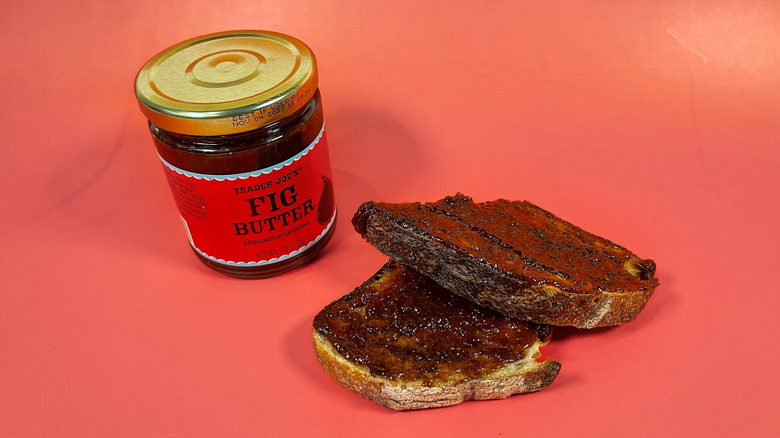 A jar of Trader Joe's fig butter next to a piece of toast spread with it and cut in half