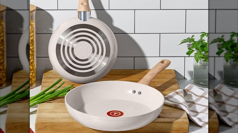Non-induction compatible T-fal Revive ceramic pans on a cutting board with a few ingredients on either side