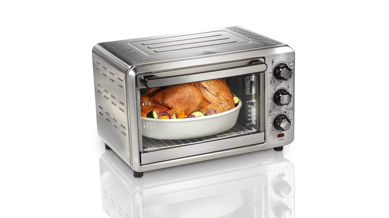 Oven-style air fryer with a whole chicken inside