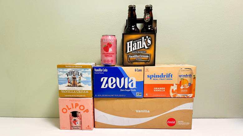 Several boxes and containers of vanilla-flavored sodas piled together in three rows