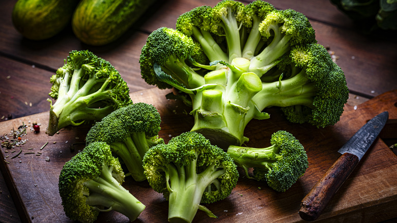 Head of broccoli cut into florets on a wooden cutting board