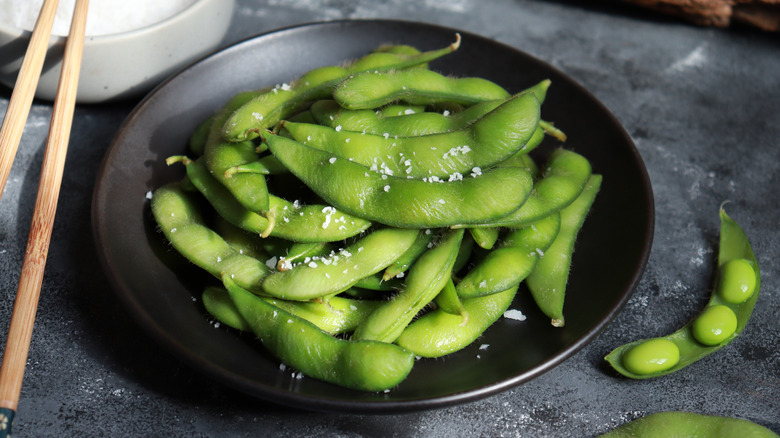 Cooked edamame pods with salt in a black bowl