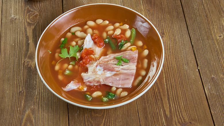 a bowl of pinto beans with a ham hock in it