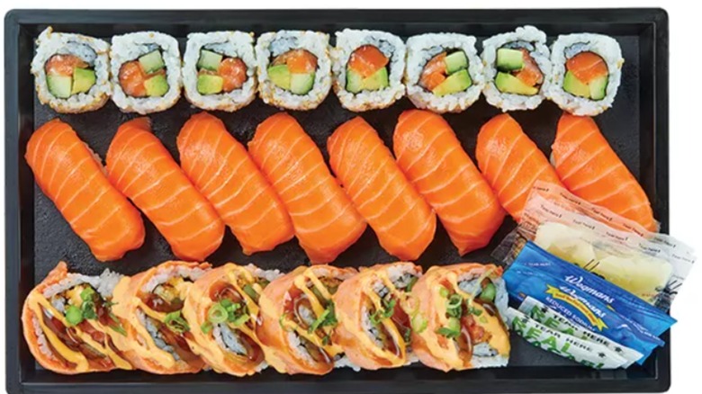 A tray of assorted sushi and sashimi pieces with salmon and avocado