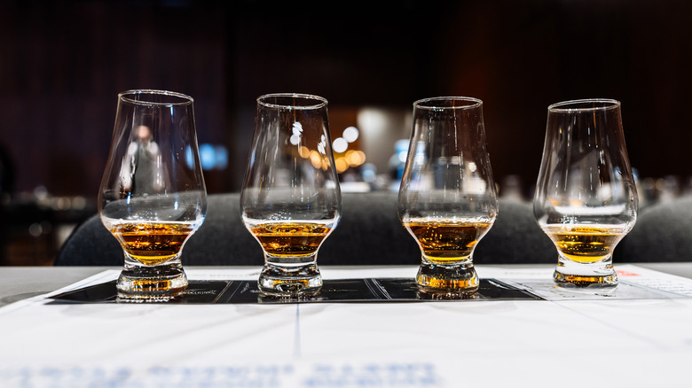 4 tulip-shaped glasses lined up filled with liquor