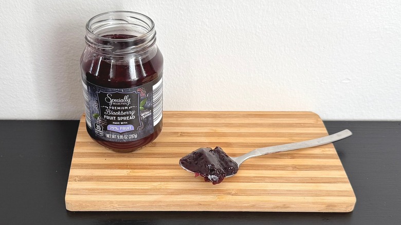 A jar of Specially Selected Premium Blackberry Fruit Spread placed on a cutting board