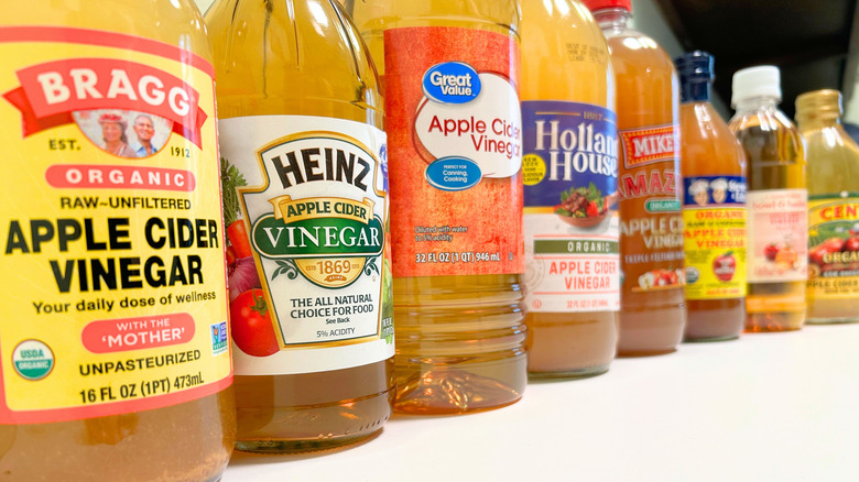 Selective focus of several bottles of apple cider vinegar from different brands lined up together