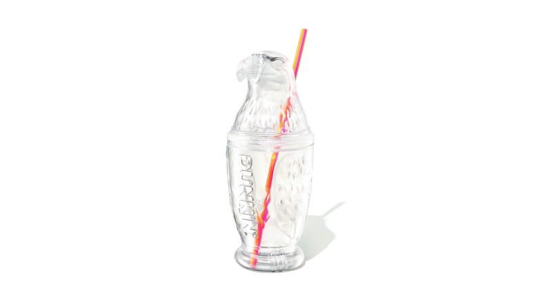 A clear tumbler shaped like a bald eagle with an embossed Dunkin' logo and orange/pink straw