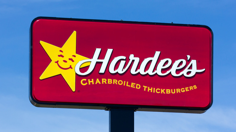 Exterior signage at a Hardee's with smiling star logo and tagline about "charbroiled thickburgers"