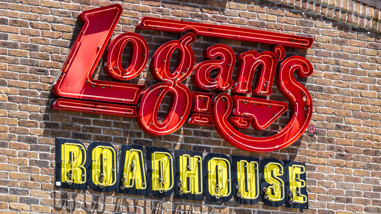 Red and yellow exterior neon sign of a Logan's Roadhouse in daylight
