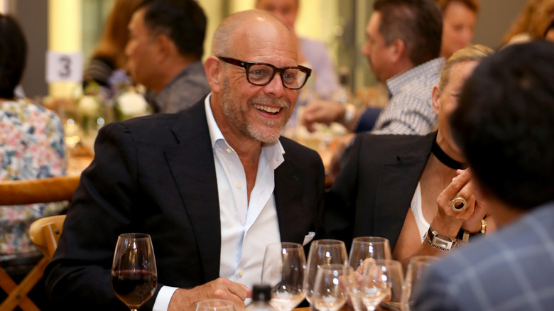 Alton Brown smiling at a dinner table