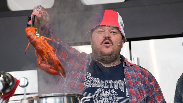 Matty Matheson holding up a lobster with tongs