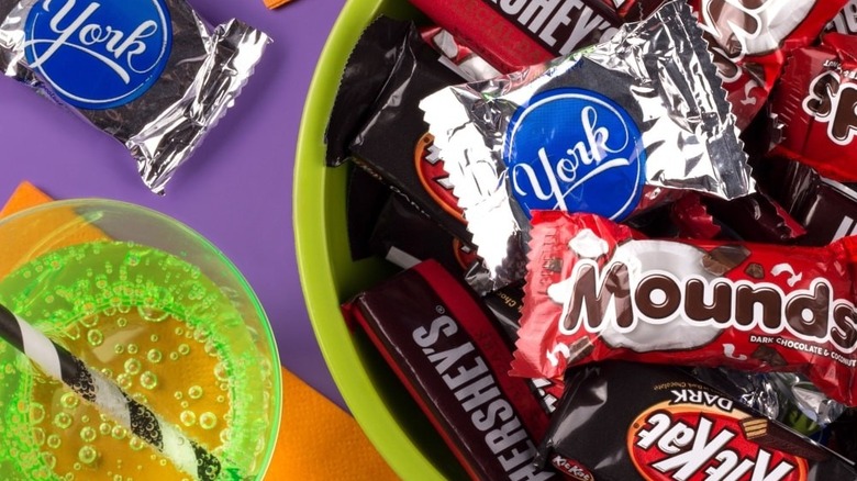 Selection of Hershey's dark chocolate bars, York patties, Dark Kit Kats, and Mounds in a green plastic bowl