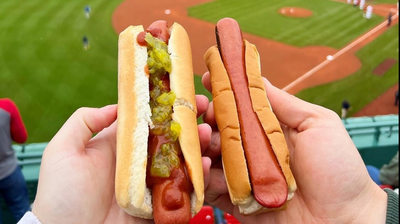 fans holding fenway frank hot dogs at ballpark