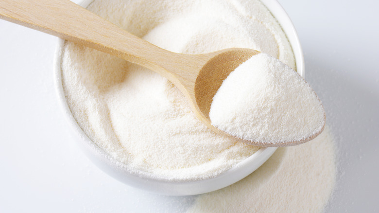 A spoonful of powdered milk being taken from a small bowl