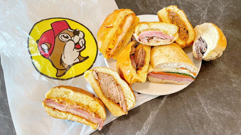Eight different halves of Buc-ee's sandwiches arrange on a plate and over a bag