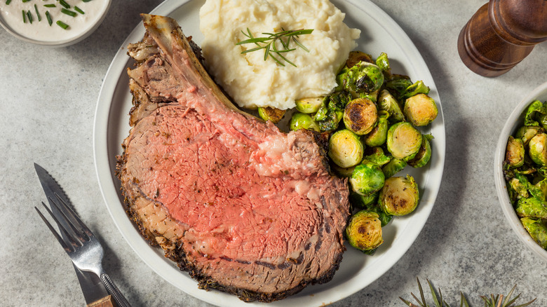 A plate of prime rib, mashed potatoes, brussels sprouts