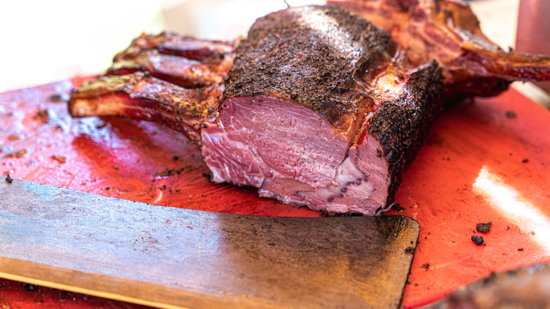 Sliced prime rib on cutting board with cleaver