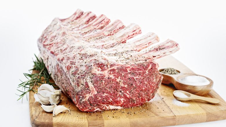 Uncooked prime rib being seasoned