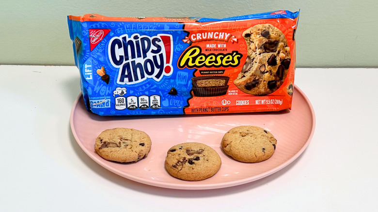 Three cookies on a plate with a bag of Chips Ahoy! Crunchy Reese's