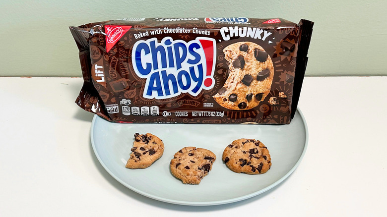 Three cookies on a plate with a bag of Chips Ahoy! Chunky