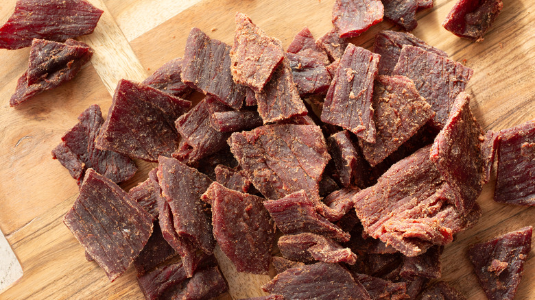 Overhead view of pieces of beef jerky on a wood cutting board