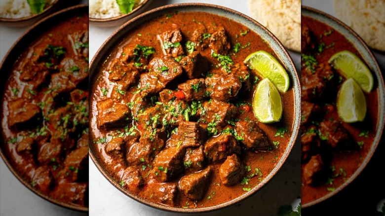 Overhead view of a bowl of carne guisada served with lime wedges
