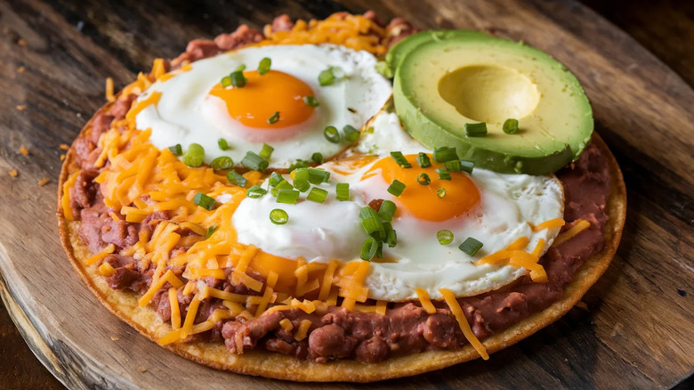 Close-up on a tostada topped with huevos rancheros and avocado
