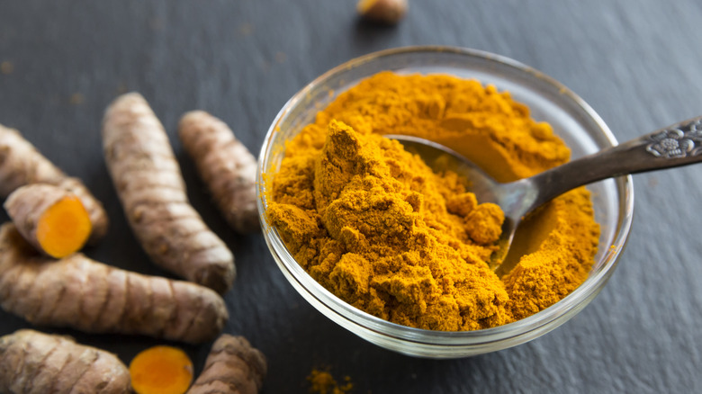 turmeric root with turmeric powder in a bowl