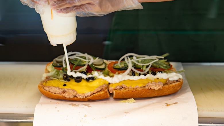 Subway employee squirting mayo onto sandwich
