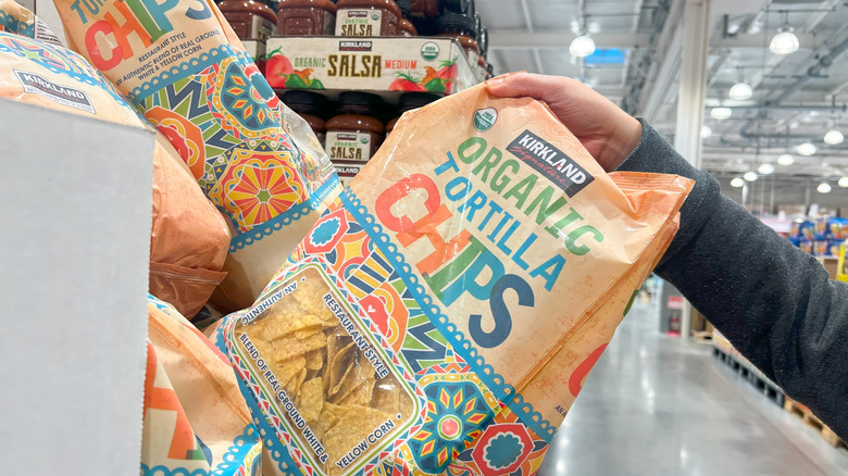 Hand pulling Kirkland organic tortilla chips from display