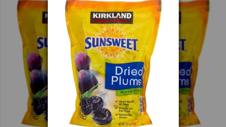 Kirkland dried plums in a yellow-orange bag on white background