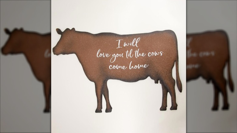 Metal Cow Wall Decor of a brown cow with writing on it