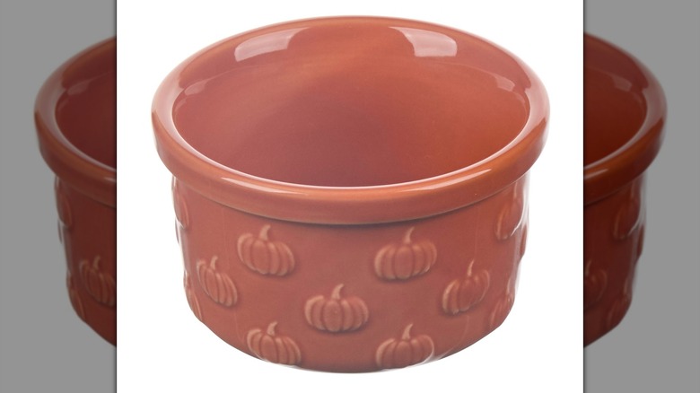An orange ramekin with pumpkins on it on a white background