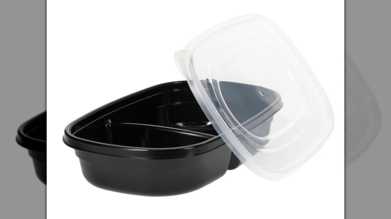 A black Meal Portions By SureFresh Medium Plastic Food Storage Container with a lid resting on its side on a white background